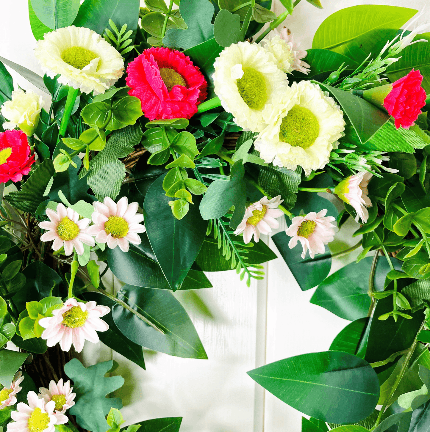 spring summer welcome door wreath with pink and white bellis daisies and greenery
