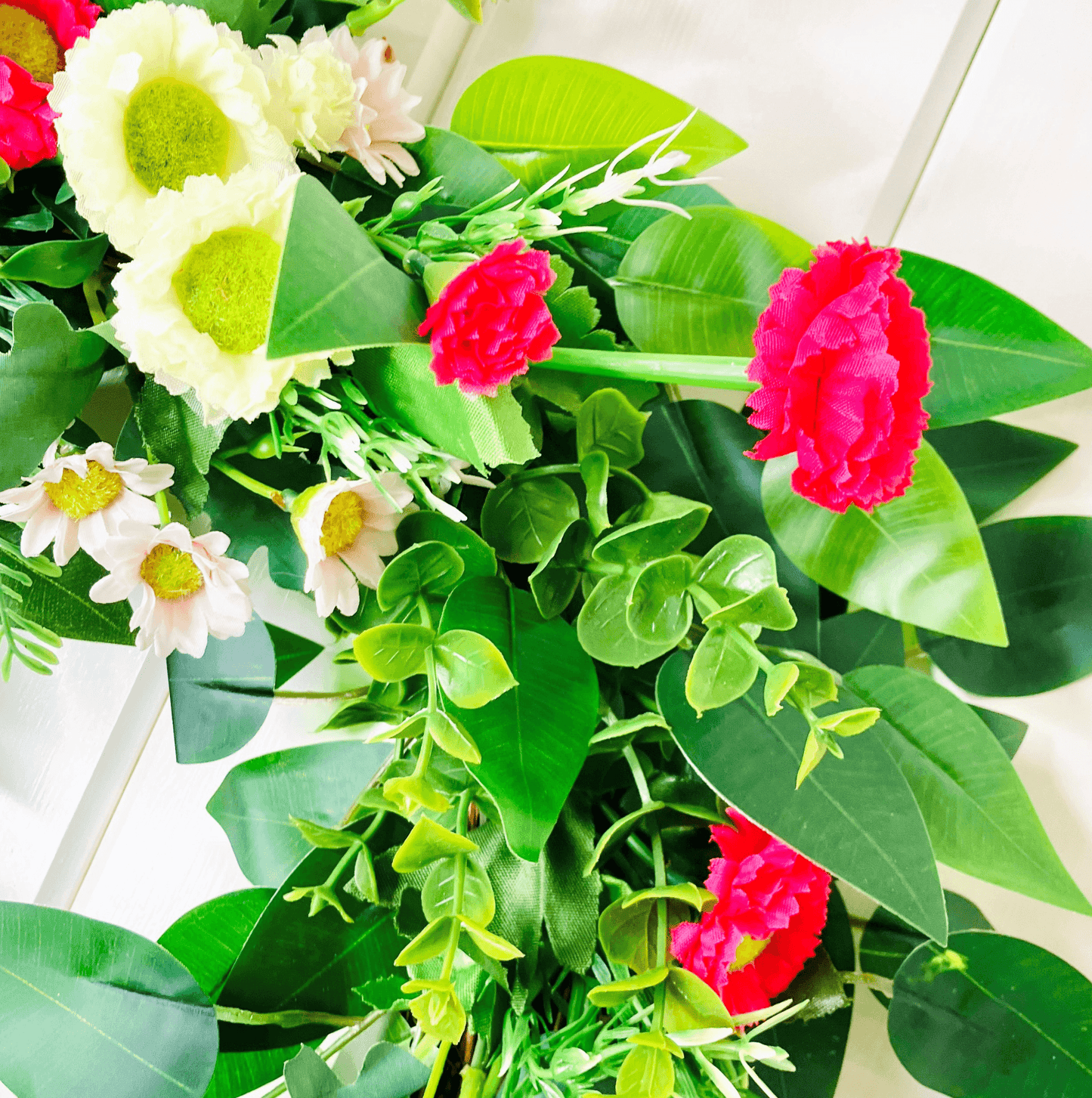 spring summer welcome door wreath with pink and white bellis daisies and greenery