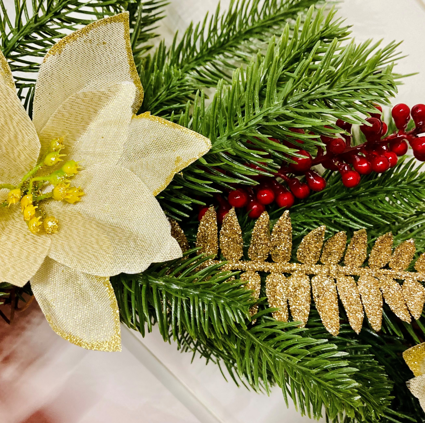 Christmas Wreath With Cream and Gold Poinsettias with Red Berries Presented On A Faux Pine Base