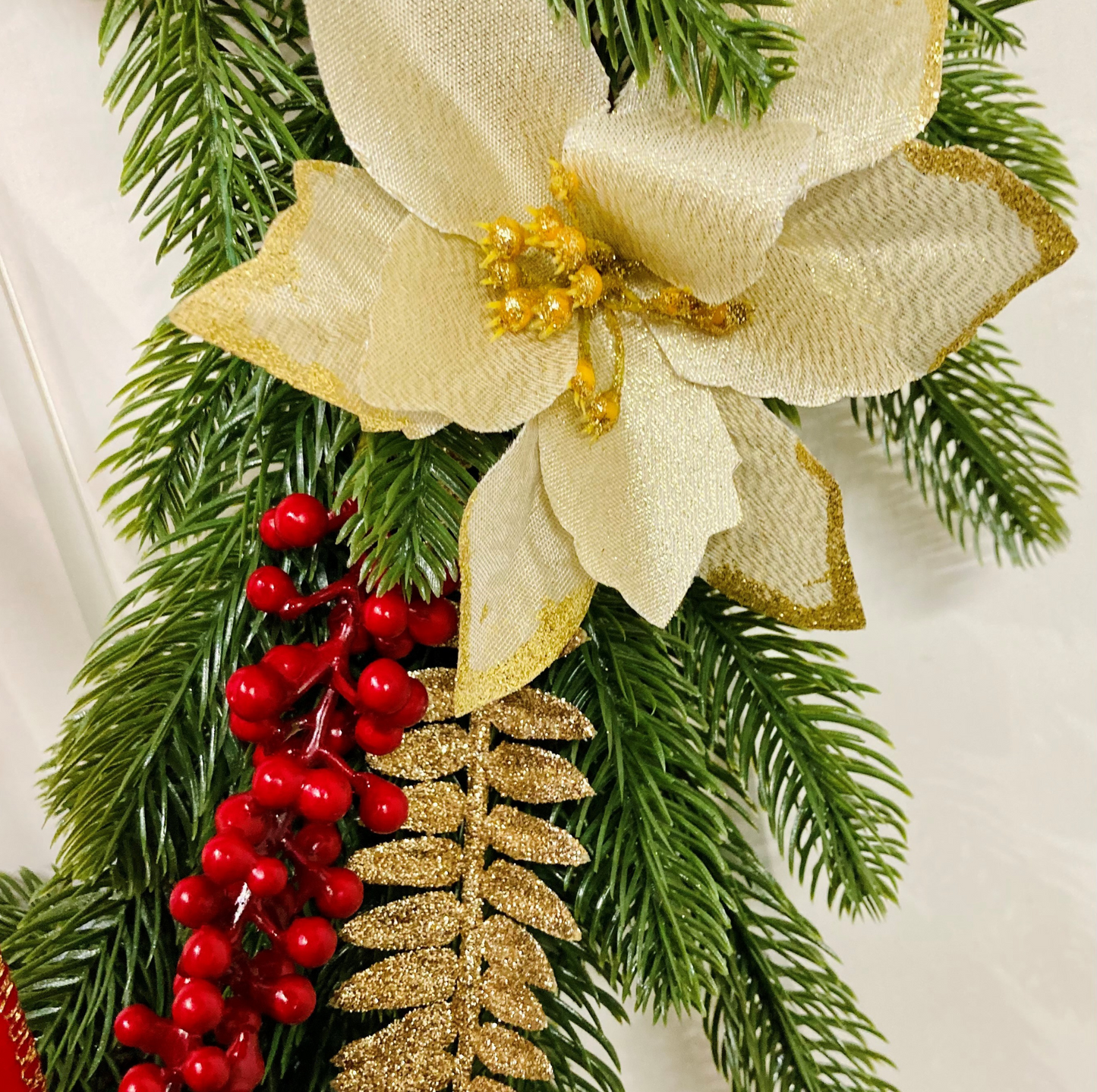 Christmas Wreath With Cream and Gold Poinsettias with Red Berries Presented On A Faux Pine Base