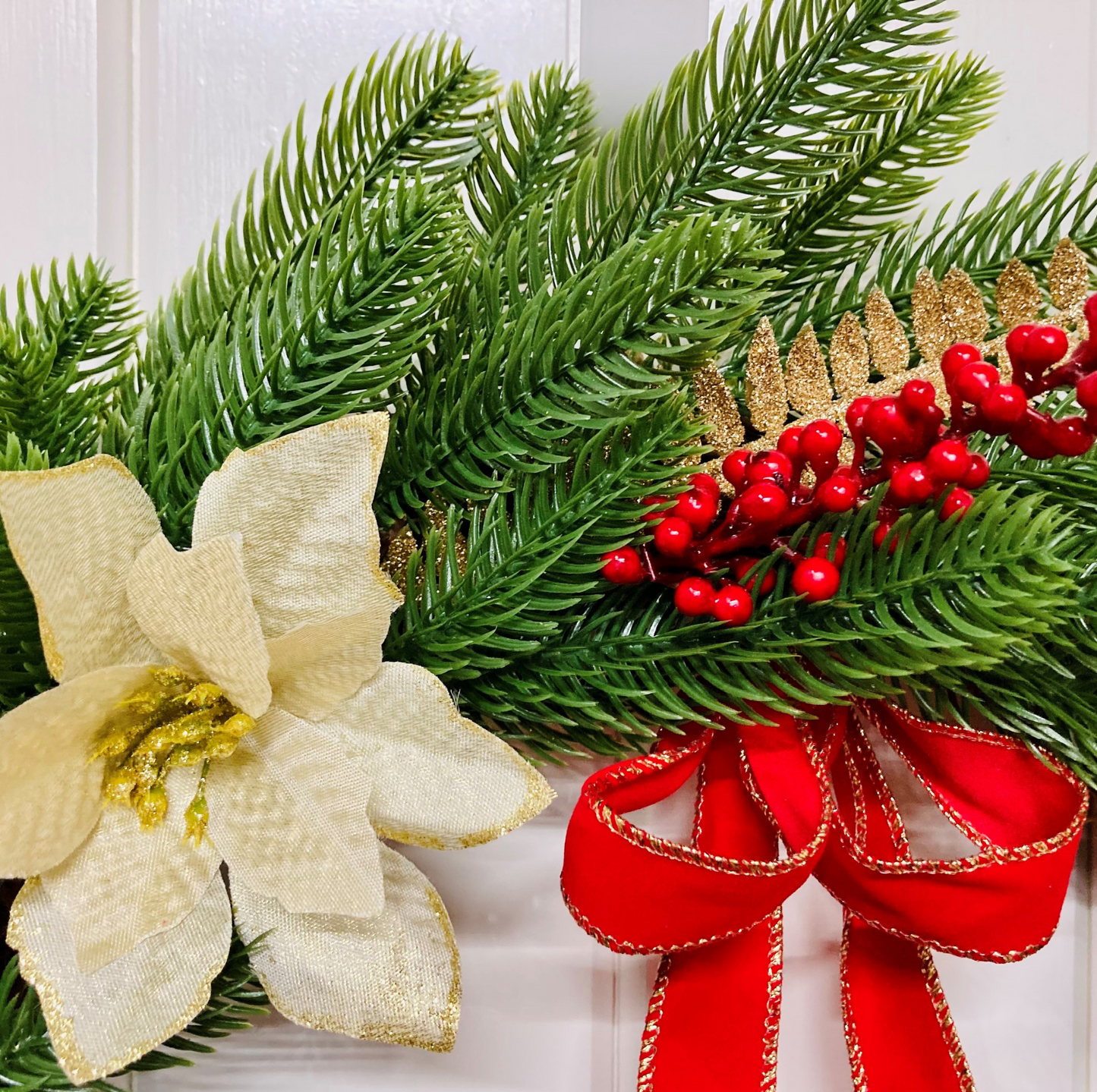 Christmas Wreath With Cream and Gold Poinsettias with Red Berries Presented On A Faux Pine Base