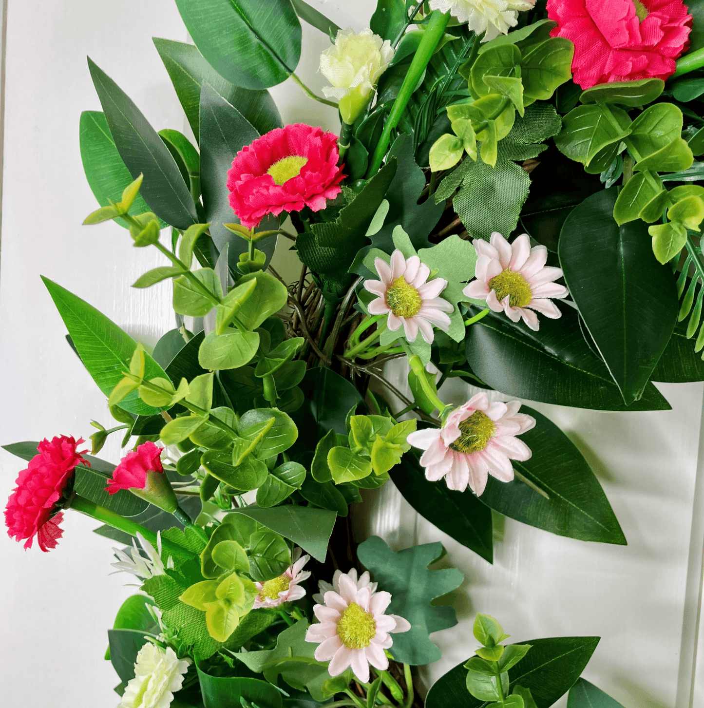 spring summer welcome door wreath with pink and white bellis daisies and greenery