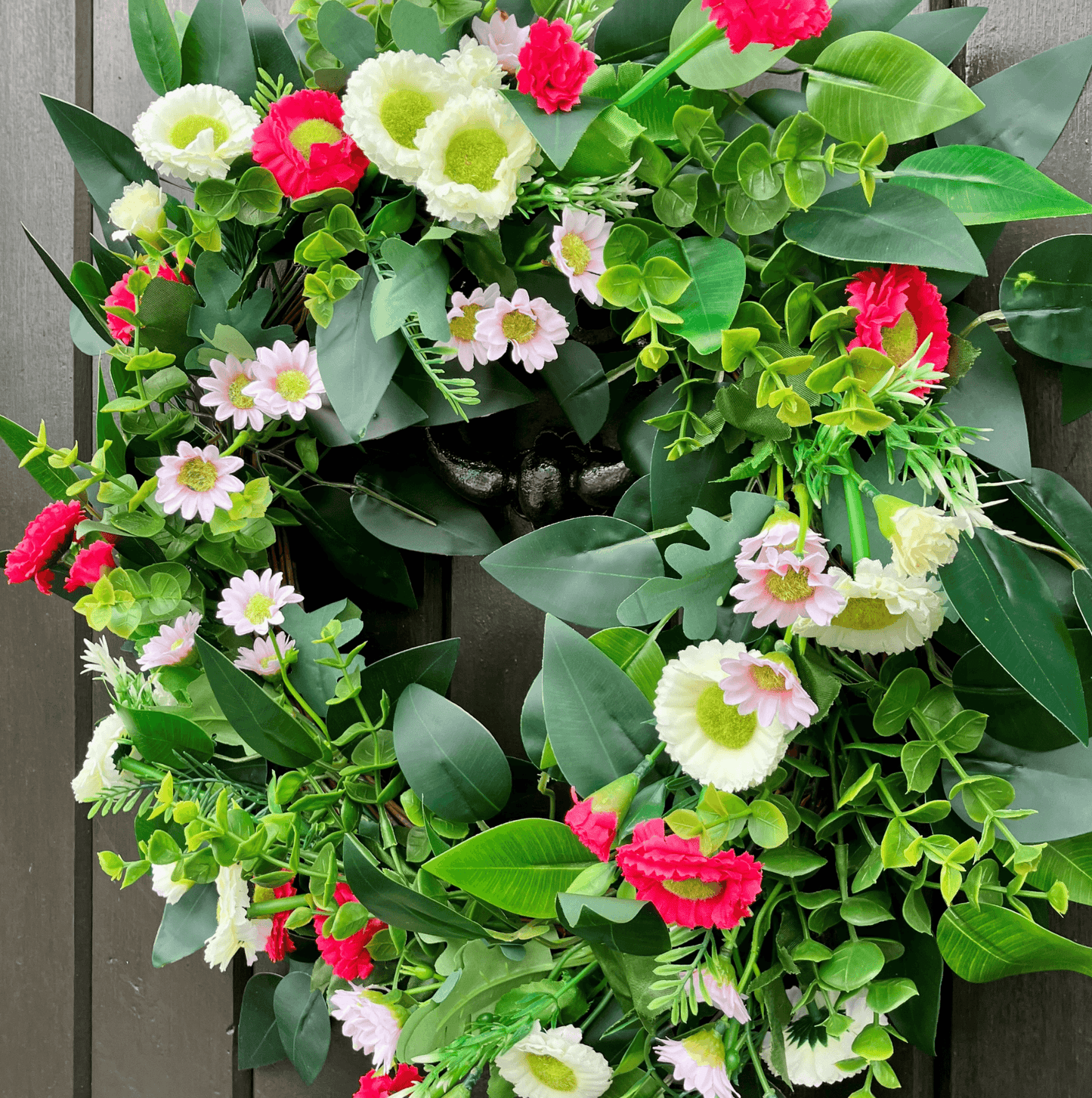 spring summer welcome door wreath with pink and white bellis daisies and greenery