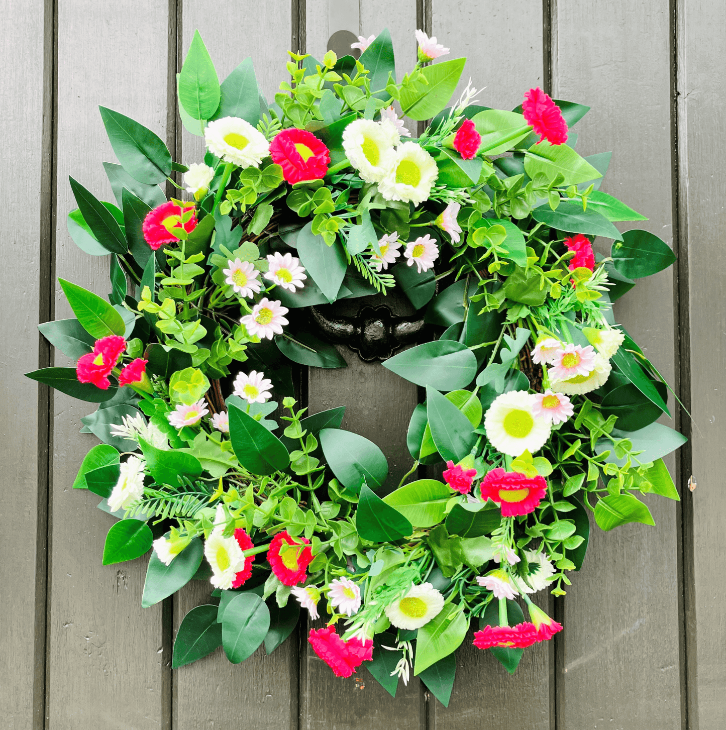 spring summer welcome door wreath with pink and white bellis daisies and greenery