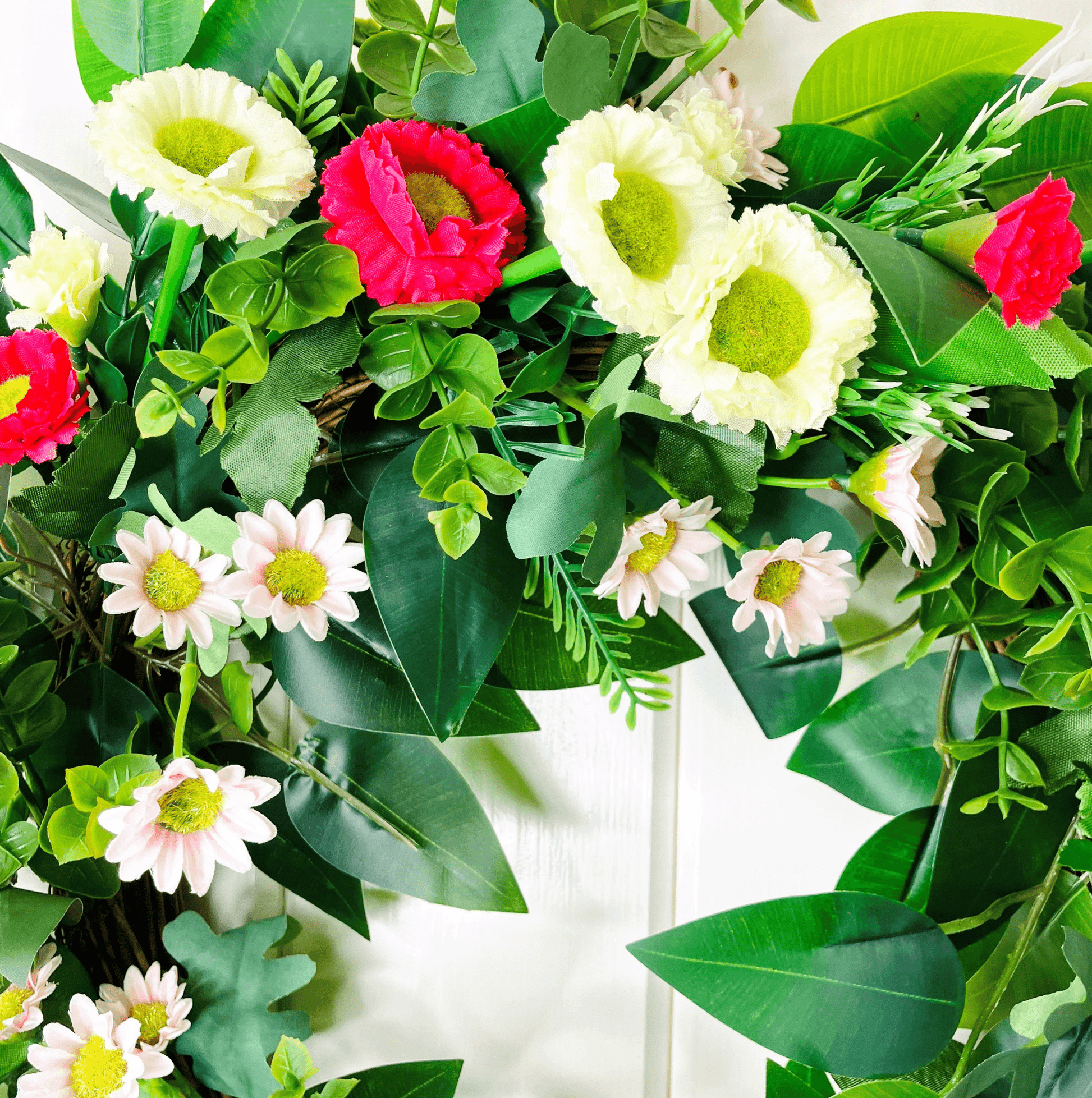 spring summer welcome door wreath with pink and white bellis daisies and greenery