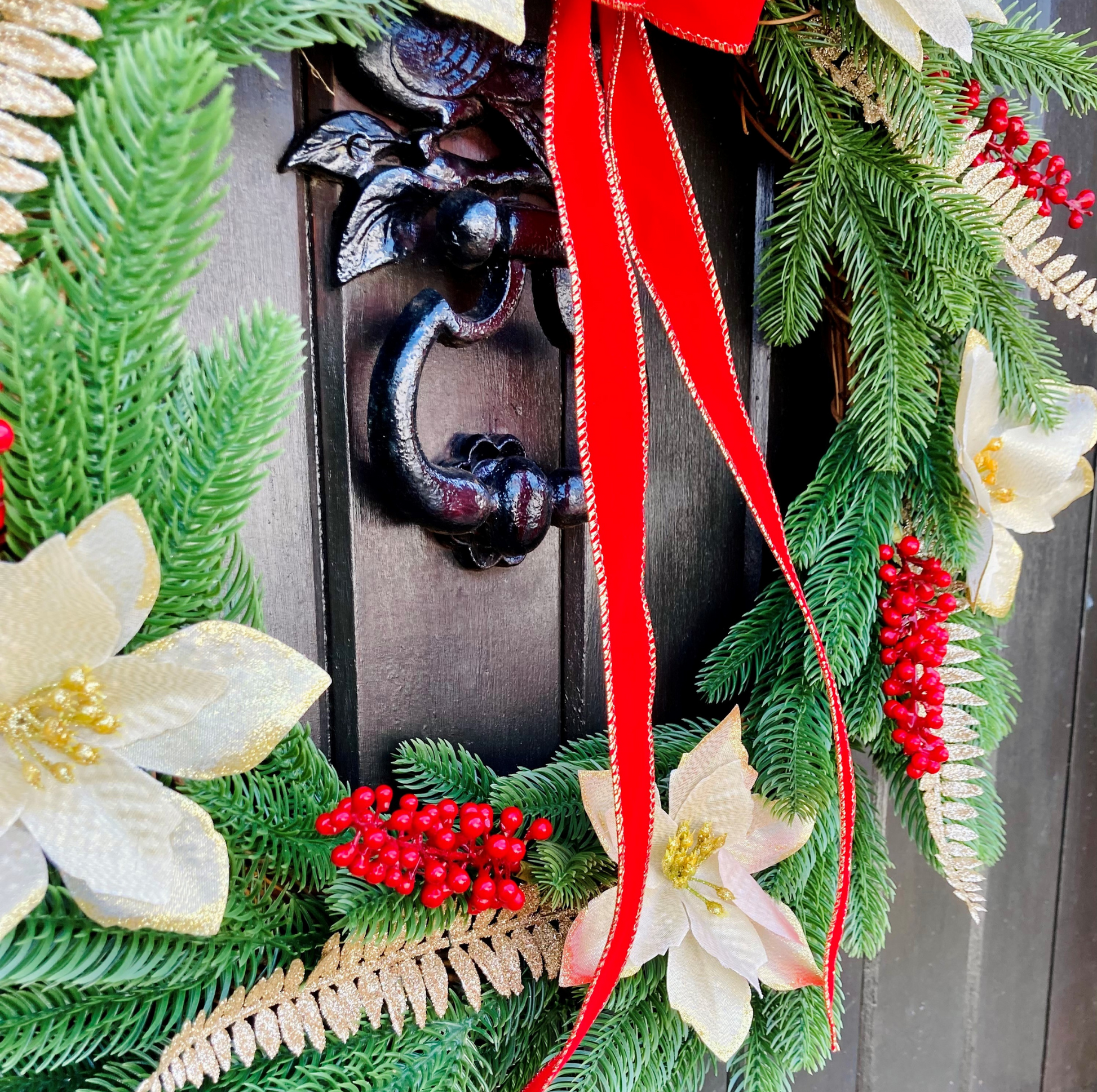 Christmas Wreath With Cream and Gold Poinsettias with Red Berries Presented On A Faux Pine Base